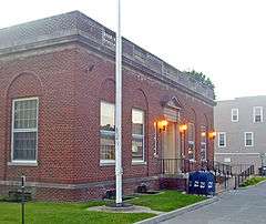 A side view of the front of a brick building with its front lamps on