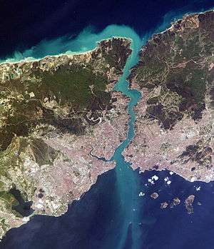 Satellite image showing a thin piece of land, densely populated on the south, bisected by a waterway