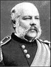 Man with moustache and large sideburns facing right in a dress uniform with awards