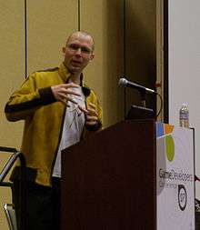 A young adult male addressing an audience behind a podium.