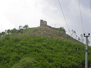 Old castle seen from downhill, with power lines in the foreground