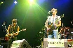 Two men playing guitars in concert