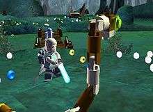 In a swamp-themed setting, a young man holds a futuristic sword-like weapon, apparently about to kill a large snake made of small plastic toy pieces. A short, somewhat cylindrical-shaped white and blue robot stands in the background. Visible in the foreground and background are many small disc-shaped objects; most of them are silver but some are gold or blue.