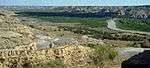 A small river meanders through a landscape of forests, bluffs, and rocky outcrops.