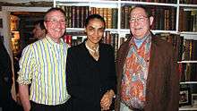 Waist high portrait of three middle aged people in the library of what could be a boat or other confined space.