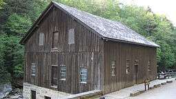 A wooden two-story building atop a stone foundation