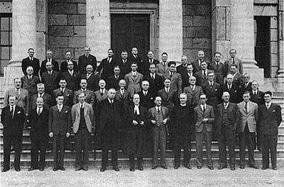 Around thirty men standing on steps.