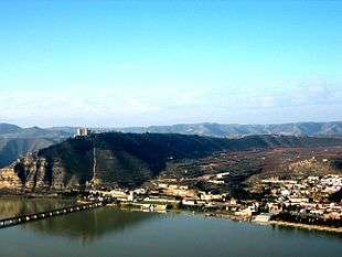 Photo of a large river, with a town on the far bank at center and right, while a large bluff rises at the left