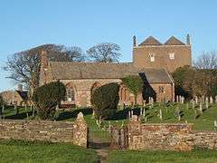 A small church seen from the south with a nave containing three three-light windows, one of which is blocked, a small chancel, and a west bellcote