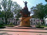 Red-and-brown statue of people on a yellow base