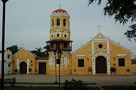 Facade of a stone church with tower painted in white and yellow.