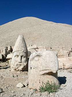 Large sculpted heads of a bird and a human lying on the ground.