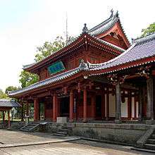 Wooden building painted red with a hip-and-gable roof.