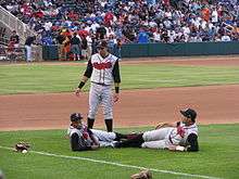 Three men wearing black caps and gray baseball uniforms with "Nashville" written across the chest in red letters on a baseball field before a game