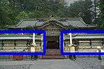 A roofed colorful fence extending to either side of a Chinese style gate