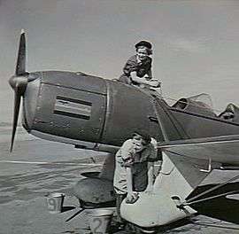 Two women in overalls sponging a single-engined monoplane