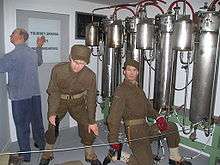 Two saboteurs and a facility employee shown adjacent to the electrolysis chambers.