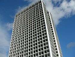 A white building stands before a blue sky with several clouds