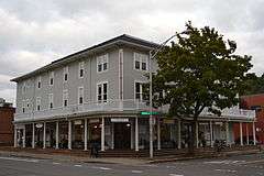 Photograph of a three-story urban building with a large veranda