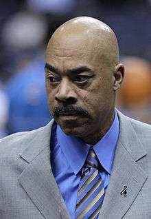 Headshot of a man, who wears grey suit, a blue shirt and a blue tie