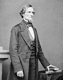 Middle-aged man in a goatee posed standing in a suit, vest and bowtie