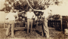 Sepia toned photograph of three teenagers posing with swords.