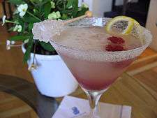 A raspberry Lemon Drop garnished with raspberry, lemon peel twist and rock candy