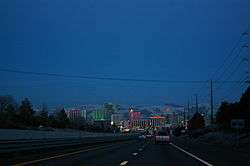 Dusk view of a freeway descending into a neon lit cityscape