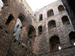 The interior of a building with three rows of windows visible and an internal partition with arches. The window arches are decorated.