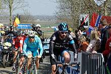 Cyclist Sir Bradley Wiggings leads a small group of riders over a cobbled road section during the race.