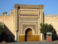 A picture of a large gate several metres high covered with various abstract designs.