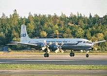 Four-engined large piston aircraft with a while fuselage, metallic belly and a blue cheatline