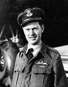 Informal head-and-shoulders portrait of man in dark-coloured battle jacket and peaked cap