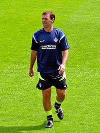 White man in football clothing on a grass field.