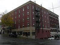 Photograph of the Panama Hotel, a squared-off brick building on a steep street. The NP Hotel stands behind.