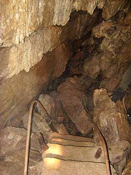 A broken concrete stair leads is submerged under a pile of loose rock, blocking the way ahead.