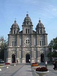 The facade of a Romanesque-style cathedral with three spires