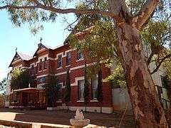 Photograph of the front of the building, with a tree in the right foreground