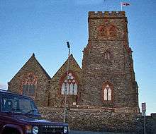 A stone church seen from the west with a broad battlemented tower