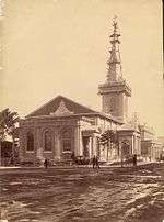 An old photo showing the church with a muddy road in the foreground and scaffolding around the spire.