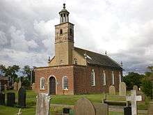 A Georgian style brick church seen from the southwest with a porch protruding in the foreground, a slim tower topped by a rotunda, and the body of the church extending beyond