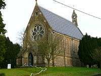 Tall stone-built church with rose window and bellcote