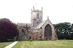 Old stone church in gothic style, flanked by trees, on an overcast day