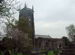 Stone building with square tower, partially obscured by trees