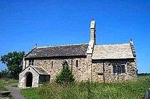 A low church seen from the south, with the nave and a porch on the left, the chancel on the right, and a bellcote on the gable between them