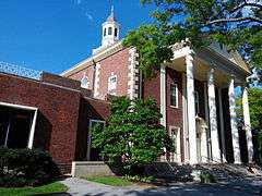 A three-story brick building with a cupola on top on a sunny summer day