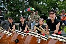 A photograph of four women in a kumi-daiko group performing in Paris, France.