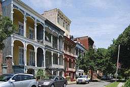 A row of attached two-story houses with ornate wooden sheltered balconies on the front.