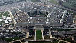 Aerial view of the huge five-sided building and its multiple rings. Parking lots and highways stretch away from it.