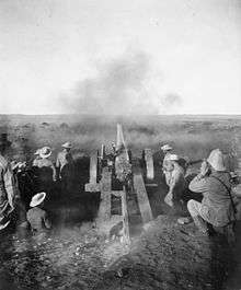 View of a naval gun on carriage from behind as shot is being fired